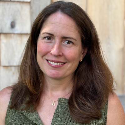 Headshot of Laura. Woman with long brown hair and has a large smile.